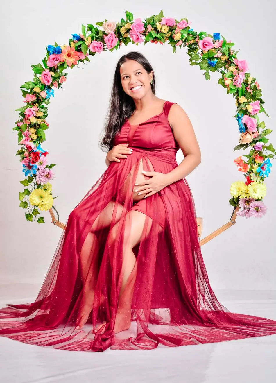 Gestante sendo fotografada em um lindo arco floral
